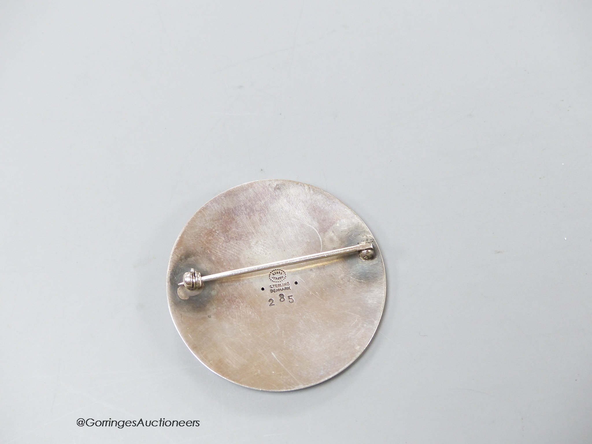 A Georg Jensen sterling circular brooch, design no. 285, depicting a man with two fish, 42mm.